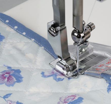 A Janome taping foot attachment stitching a narrow blue fabric tape binding onto a quilt.