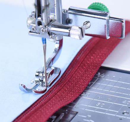 A Janome adjustable zipper foot sewing closely alongside a red zipper on blue fabric.